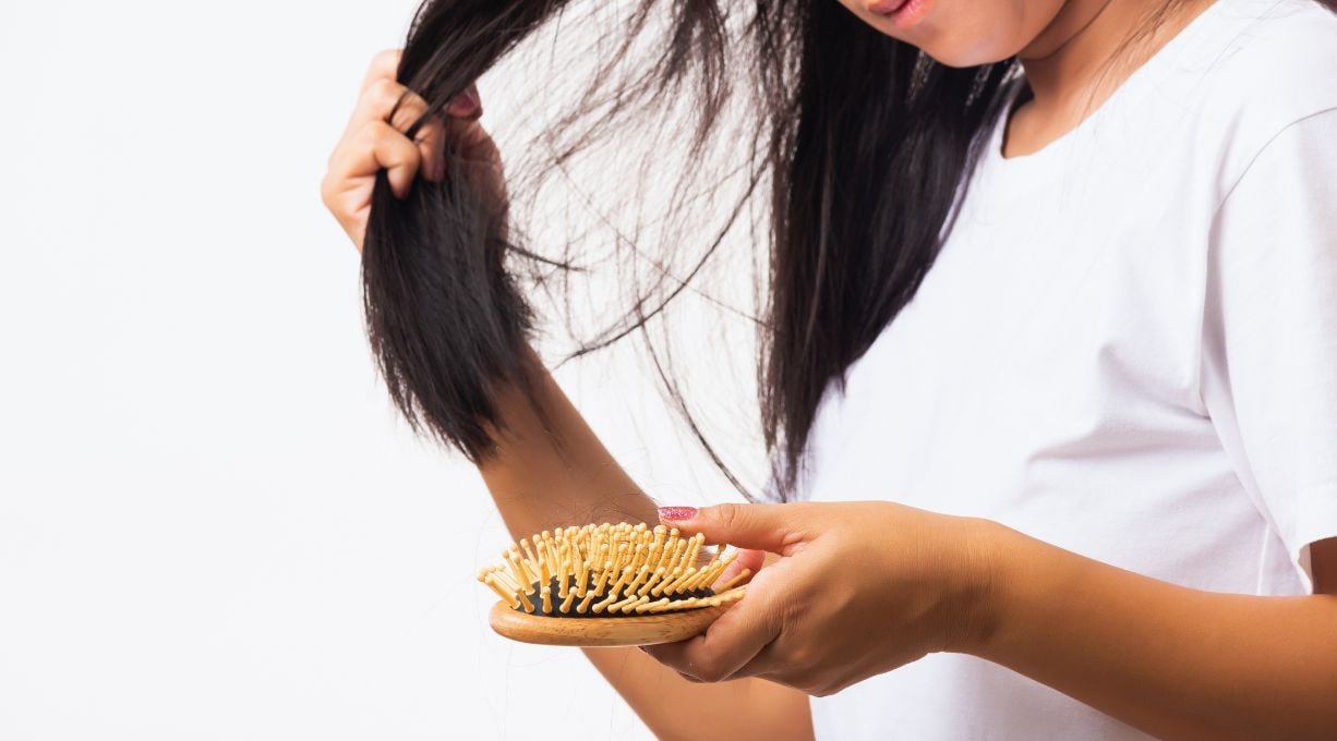 Femme se tenant les cheveux après avoir brossé ses cheveux et ayant sa brosse dans une main