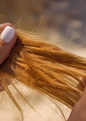 Femme aux cheveux longs roux tenant les longueurs entre ses mains