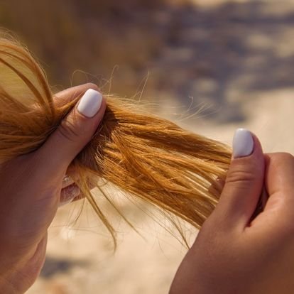 Femme aux cheveux longs roux tenant les longueurs entre ses mains