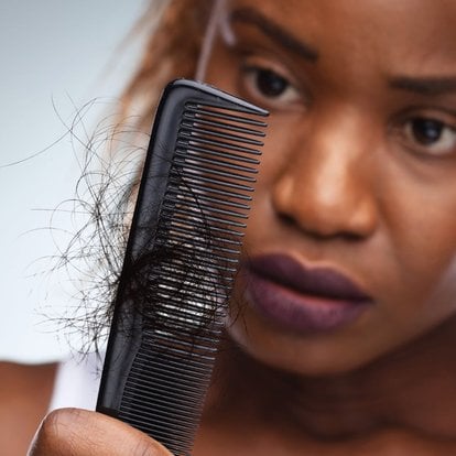 femme regardant son peigne ayant des cheveux dessus