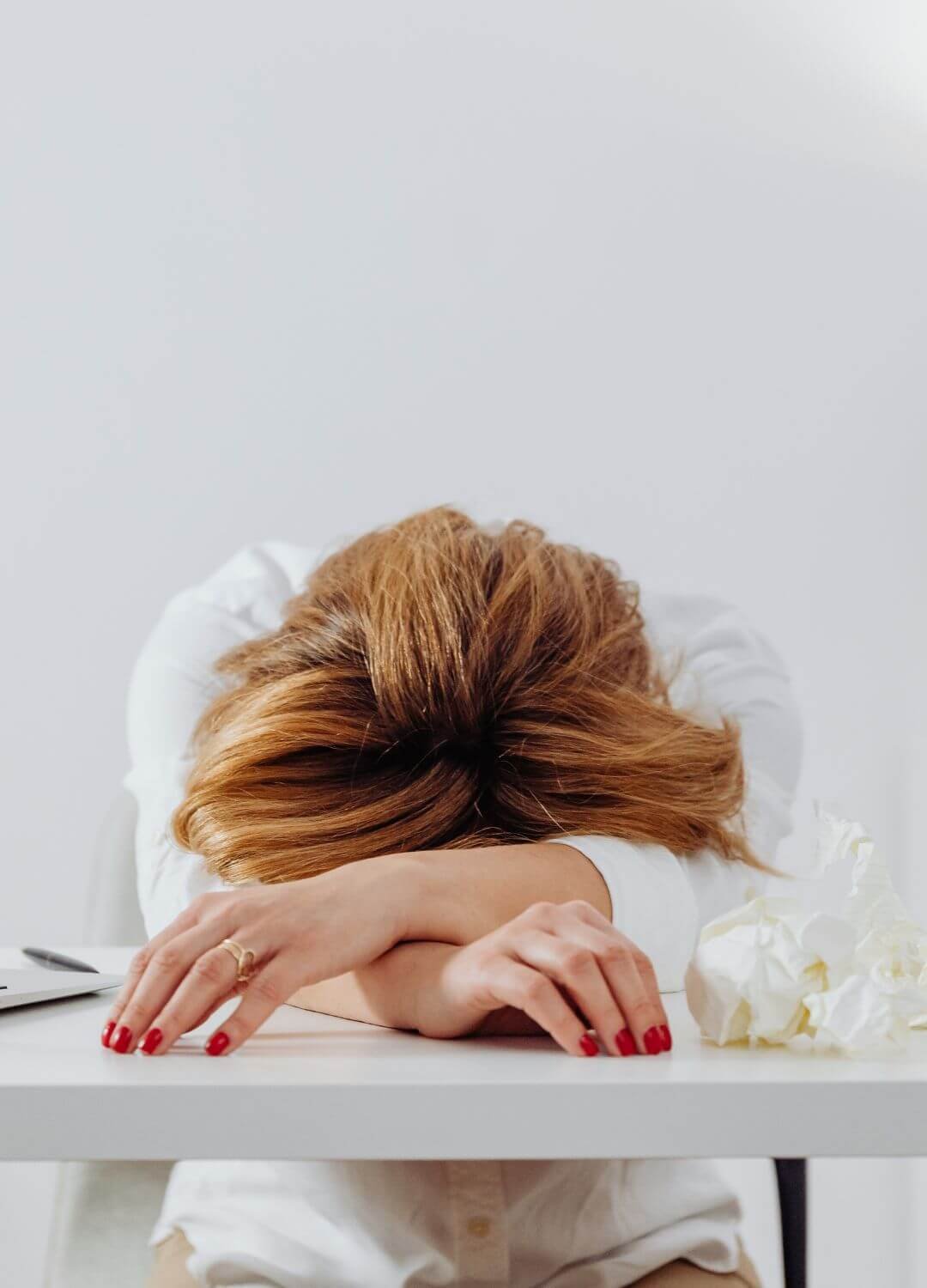 Femme fatiguée ayant la tête dans ses bras sur son bureau