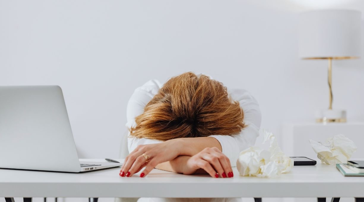 Femme fatiguée ayant la tête dans ses bras sur son bureau