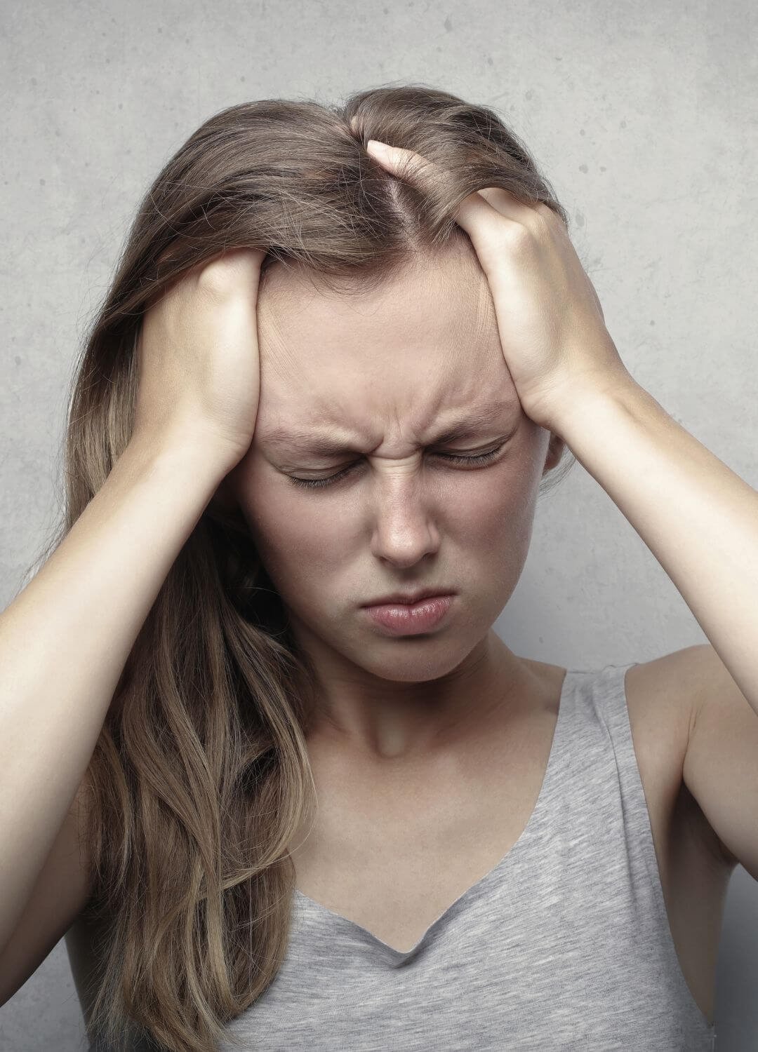 Femme se tenant la tête avec les mains dans ses cheveux