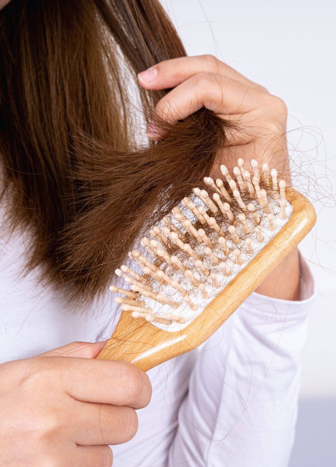 Femme se coiffant et retrouvant des cheveux morts sur sa brosse