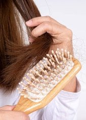 Femme qui se brosse les cheveux et constate des cheveux morts sur sa brosse