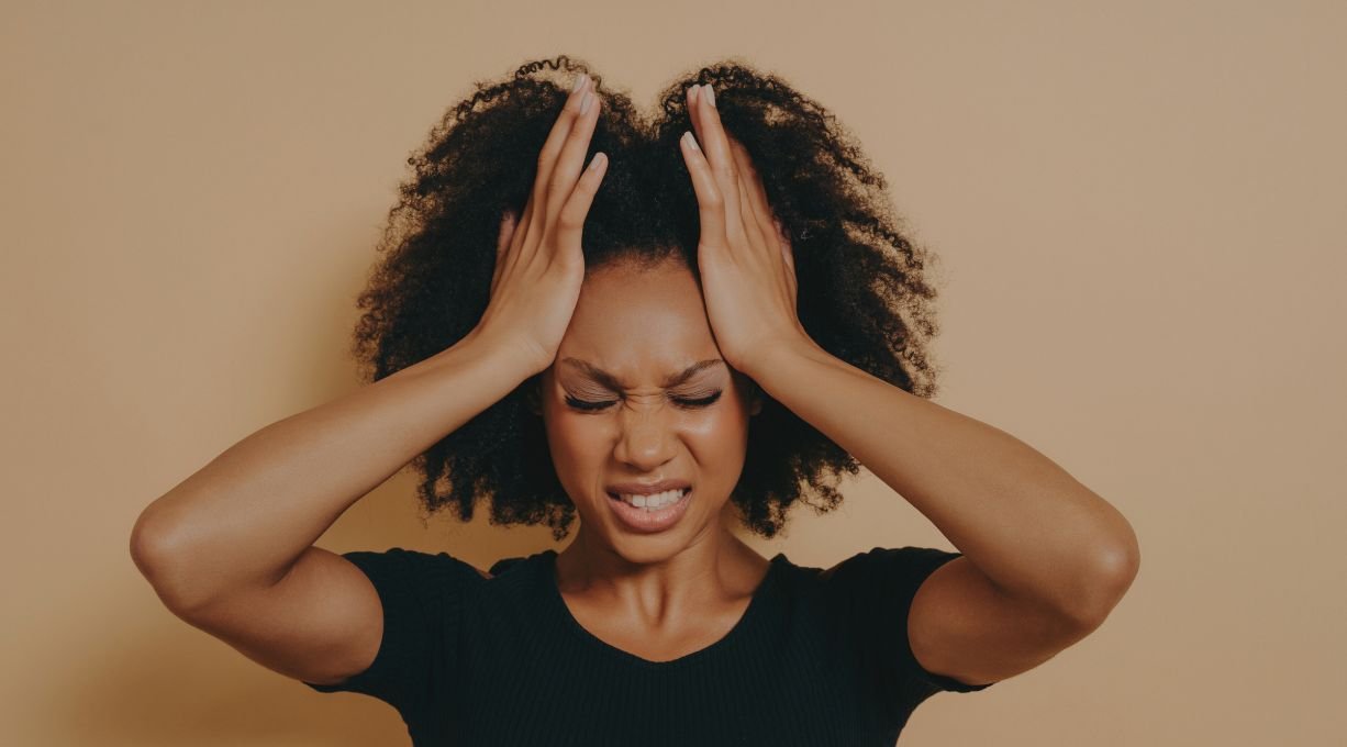 Femme aux cheveux afro se tirant les cheveux et faisant une grimace