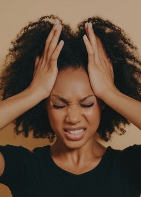 Femme aux cheveux afro se tirant les cheveux et faisant une grimace