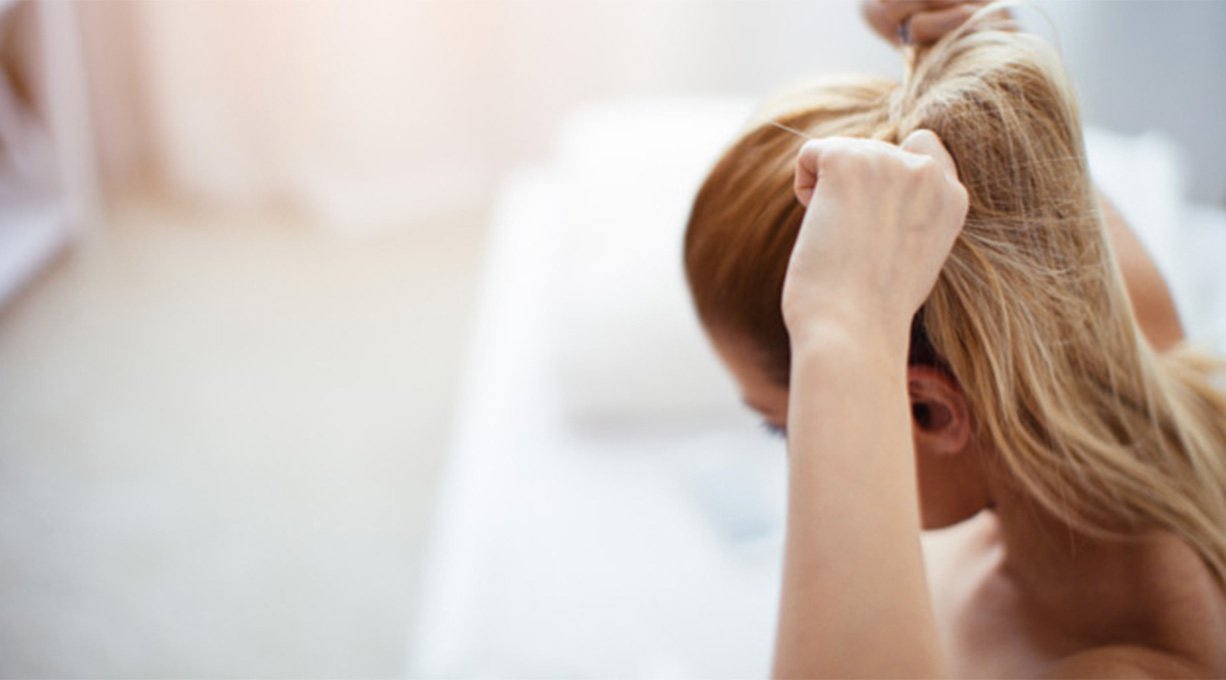 femme se faisant une queue de cheval