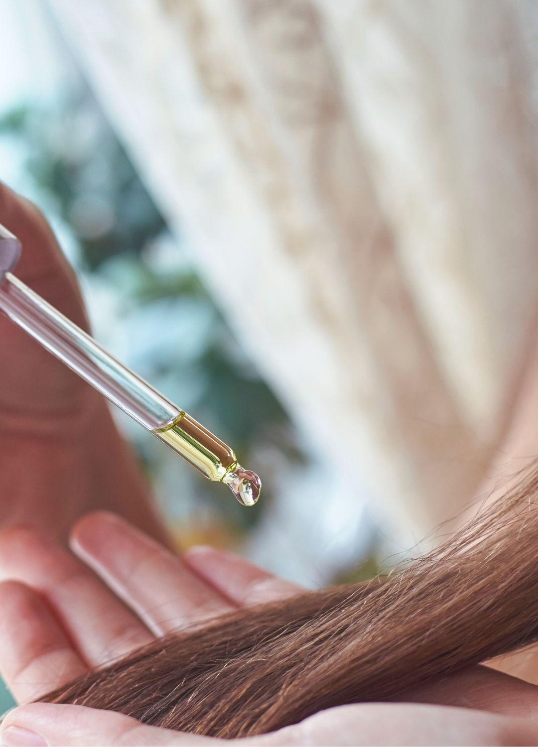 femme appliquant un sérum à l'huile de ricin sur ses cheveux