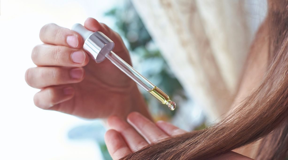 femme appliquant un sérum à l'huile de ricin sur ses cheveux