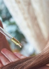 femme appliquant un sérum à l'huile de ricin sur ses cheveux