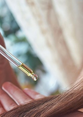 femme appliquant un sérum à l'huile de ricin sur ses cheveux